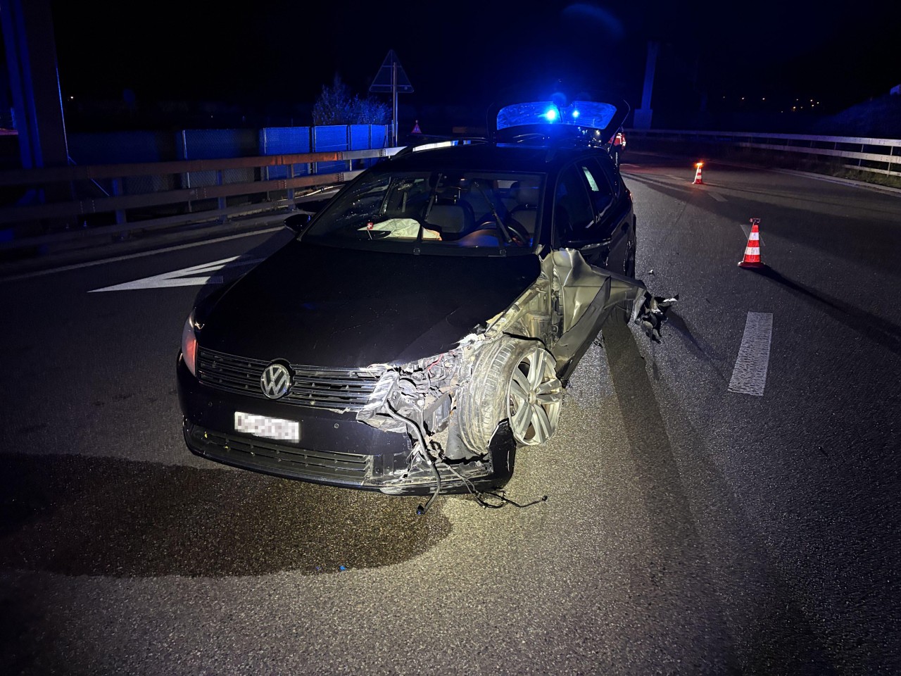 Beschädigtes, schwarzes Auto auf einer Strasse. Vorne links starke Beschädigung.