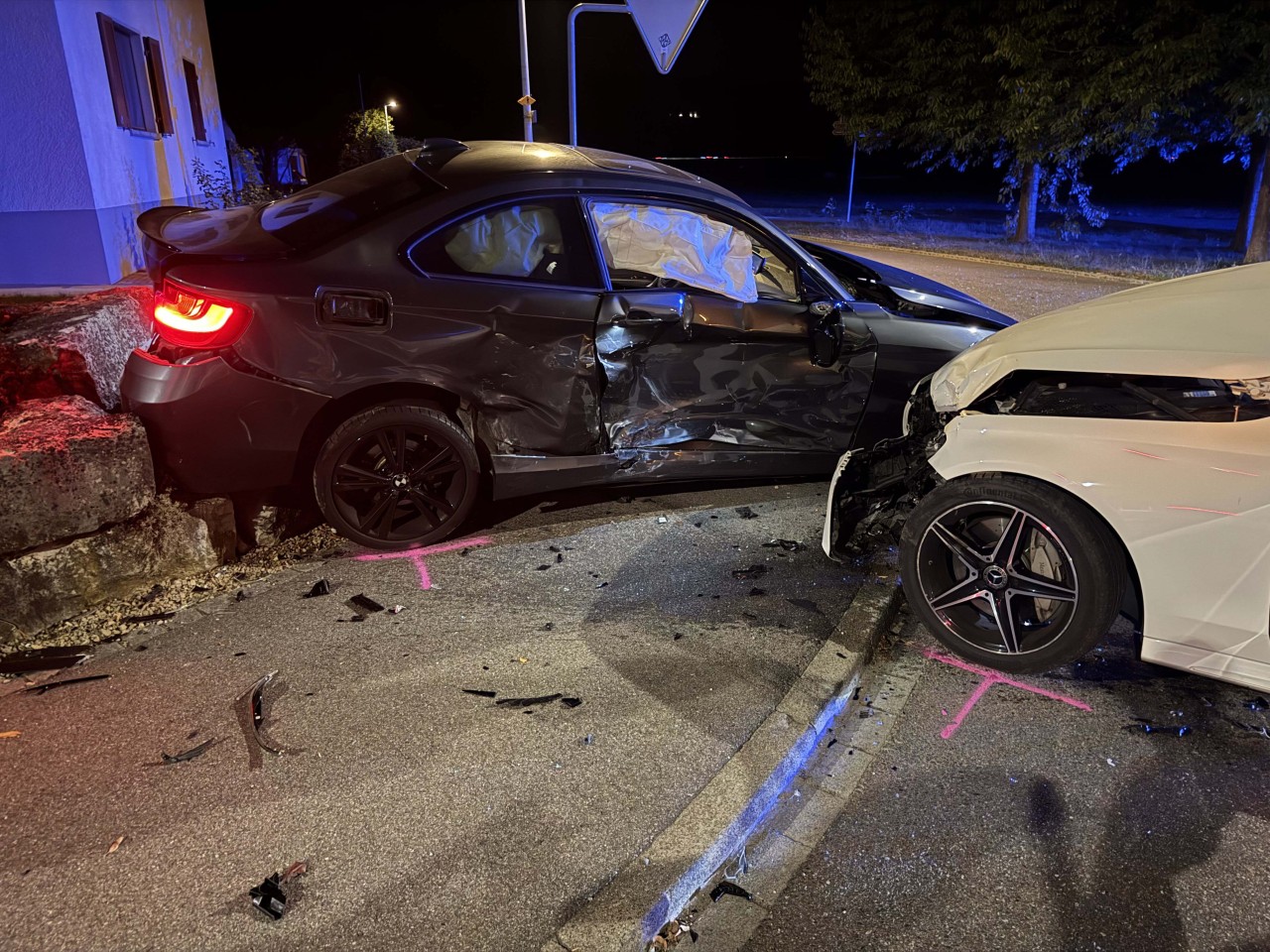 BMW, welcher seitlich stark beschädigt ist. Zudem ein weisser Mercedes ersichtlich, bei welchem die Front eingedrückt ist.