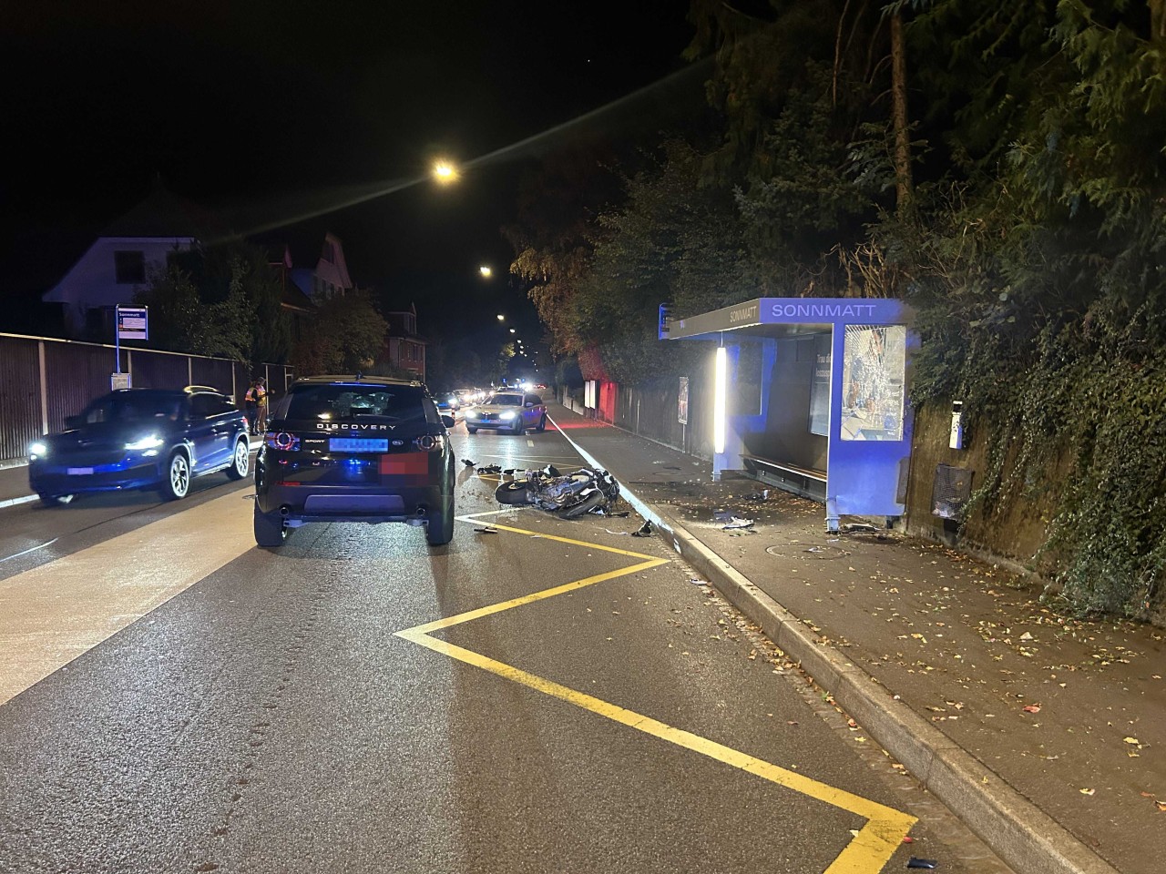 Beschädigtes Auto sowie beschädigtes Motorrad auf der Strasse. Buswartehäuschen ebenfalls beschädigt durch Kollision.