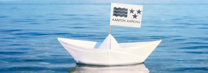 Papierschiff mit Aargauer Wappen im Wasser