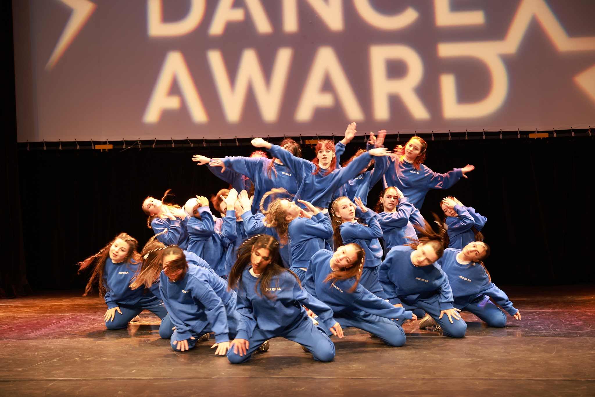 Tanzgruppe in blauen Traineranzügen verweilt in einer Pose