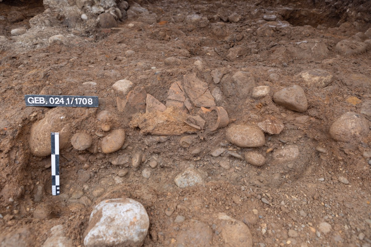 Die mehrheitlich schon geborgene Amphore in ihrer Fundlage. Zu sehen sind Scherben des Bauchs mit dem darin enthaltenen Sediment.