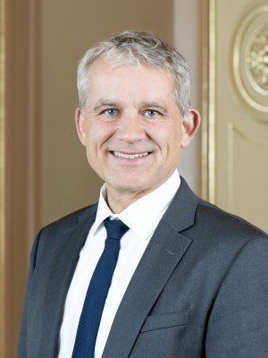 Bild von Bundesrat Beat Jans im Anzug in einem alten Saal.