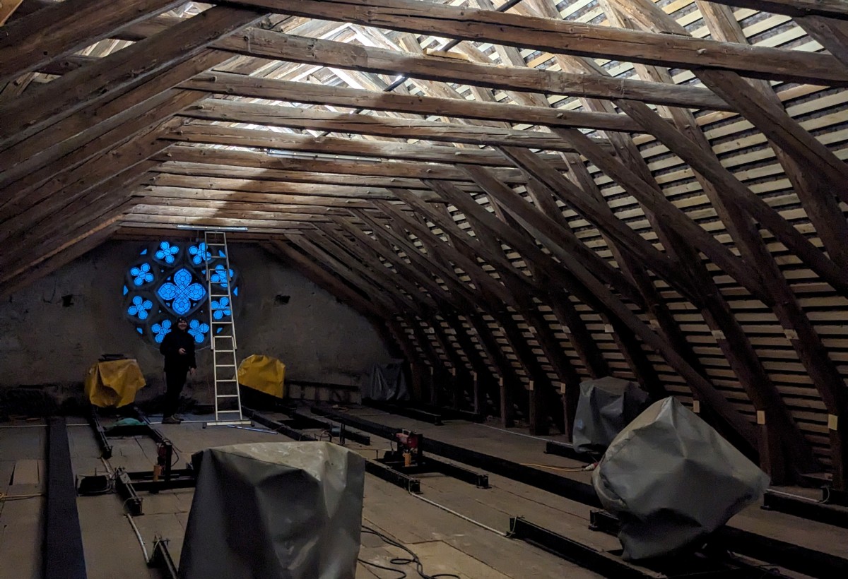 Dachstuhl eines Gebäudes mit Holzbalkenkonstruktion, zentrales blaues Stuckdetail aus dem Rathaus Brugg.
