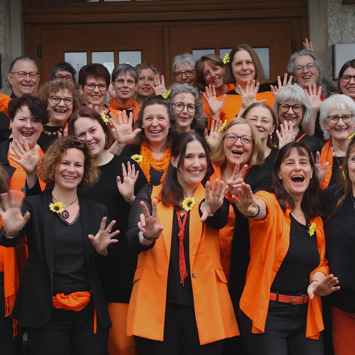Lächelnde Frauen in schwarz-oranger Kleidung.