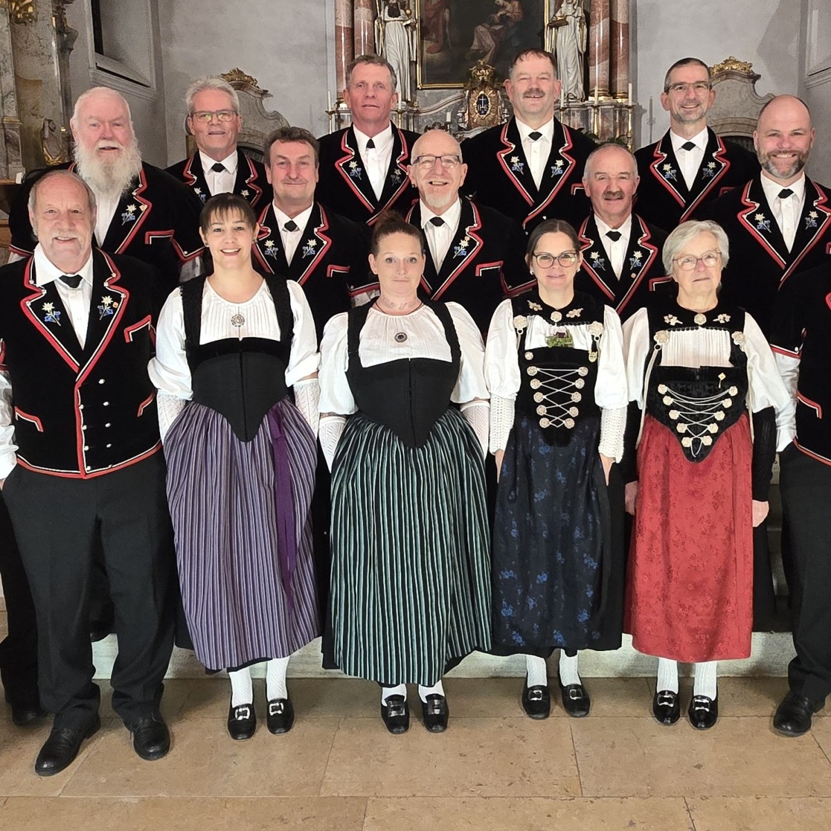 Männer und Frauen in Tracht stehen aufgereiht.