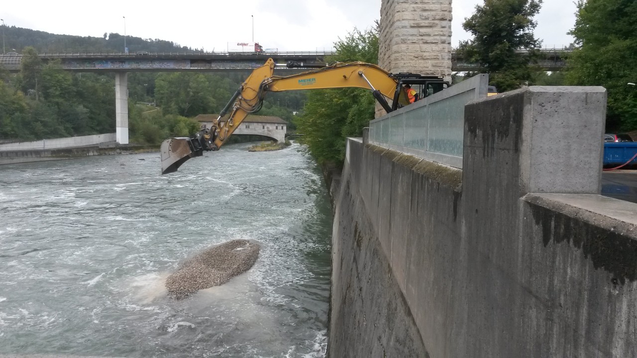 Bagger schüttet Kies in Limmat.