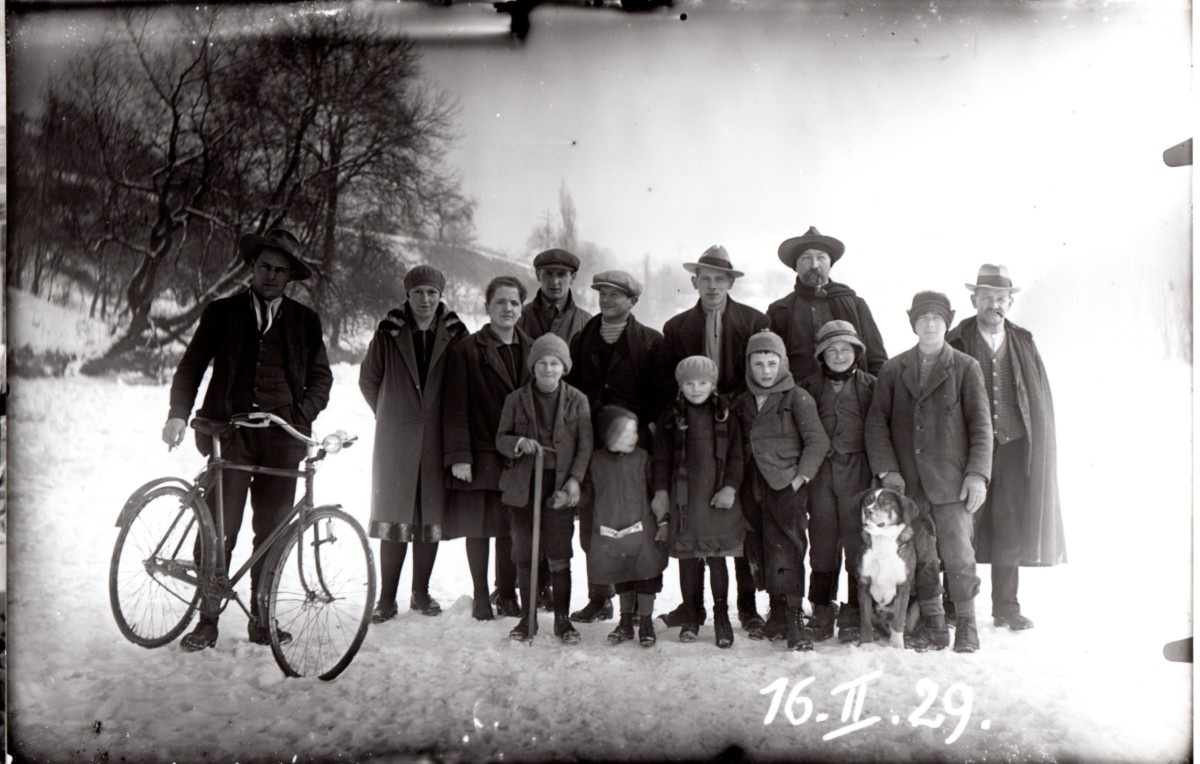 Vergilbtes Schwarz-Weiss Bild einer Gruppe von Männern, einer mit einem Fahrrad
