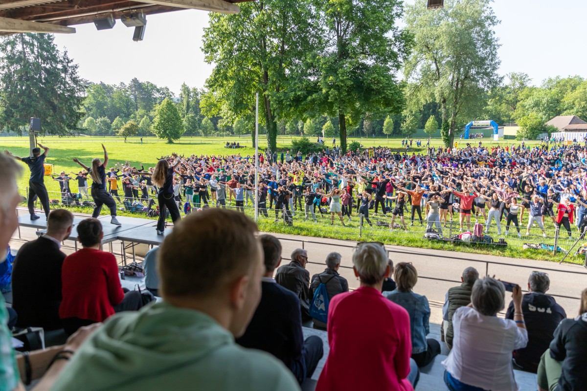 Blick aus der Zuschauertribüne auf das Spielfeld mit Jugendlichen bei der Aufführung eines flash mob