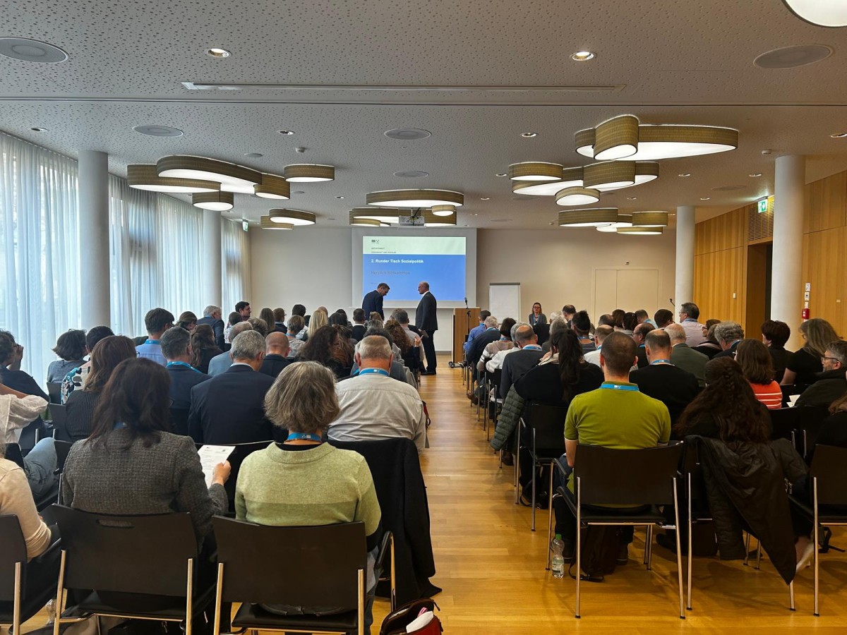 Saal mit vielen Leuten und einem Podium