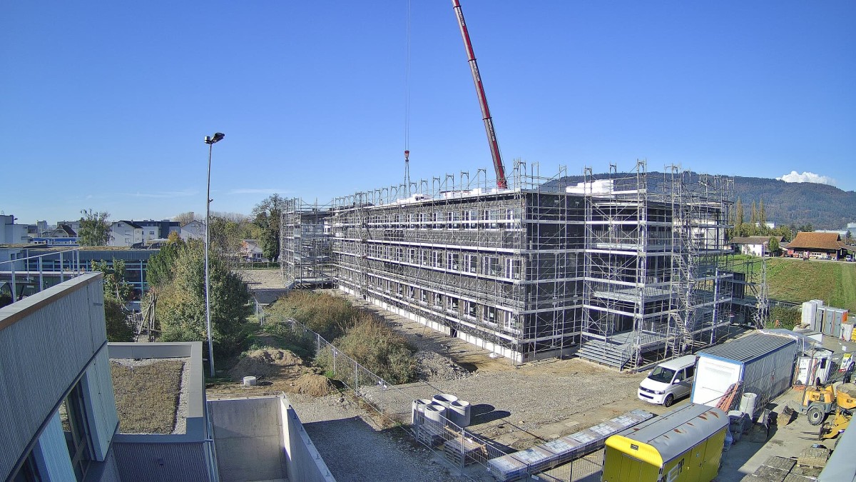Der Bau ist eingerüstet, im Hintergrund ist ein roter Kran ersichtlich.