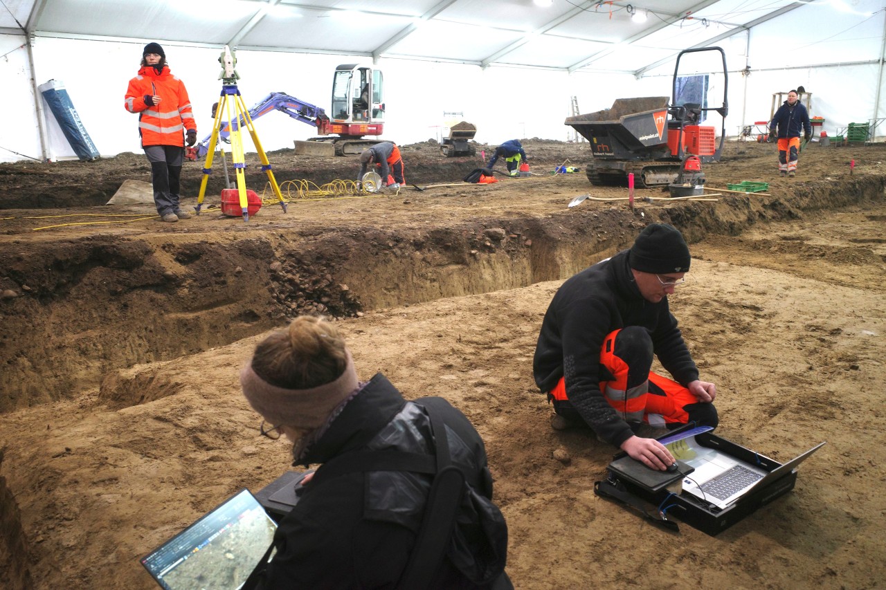 Archäologen, die in einem weissen Zelt Daten in einen Computer eingeben.