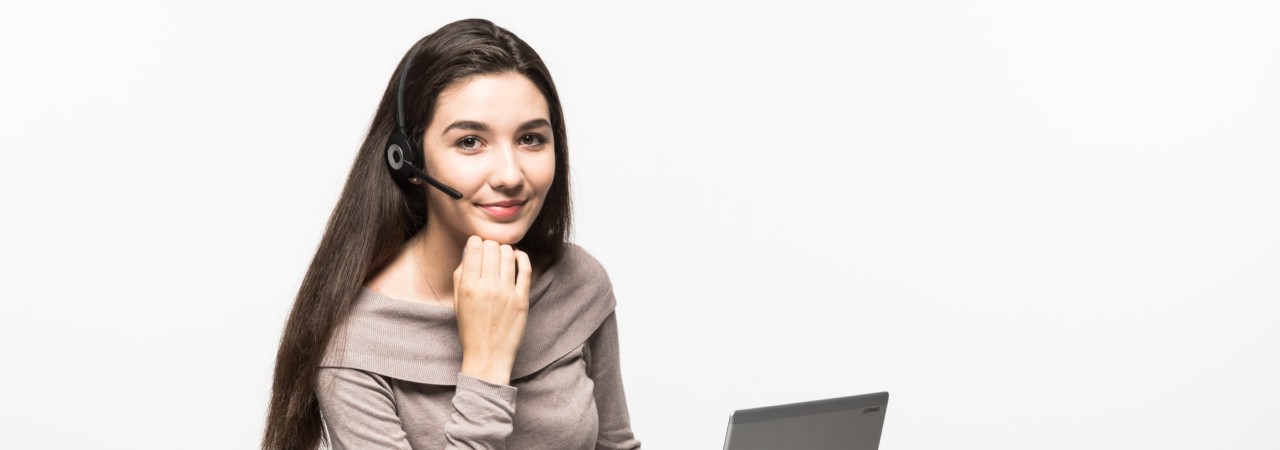 Kauffrau sitzt auf einem Bürostuhl mit Laptop und Headset.