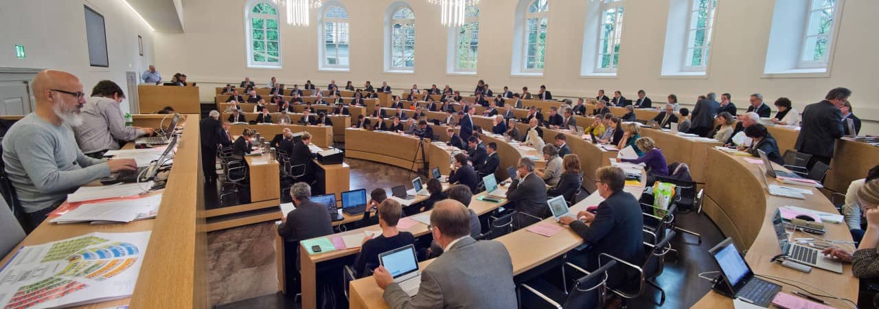 Blick aus dem rechten Flügen in den Grossratssaal. Man sieht alle Grossräte sitzen sowie auch die Medienschaffenden ganz rechts im Bild. 