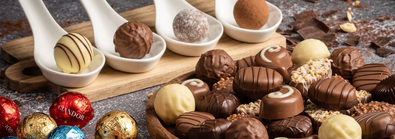 Verschiedene Praliné Schokoladen. Weiss, Braun, dunkel mit Verzierungen. Auch welche in farbiger scheinender Verpackung, rot, blau und gold.