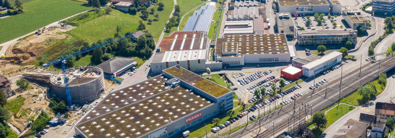 Vogelperspektive auf einen Gebäudekomplex mit fünf flachdach Gebäuden. Am grössten davon ist der Schriftzug Franke zu erkennen.