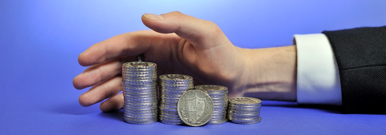 Hand, welche Münzen schützend umgreift 