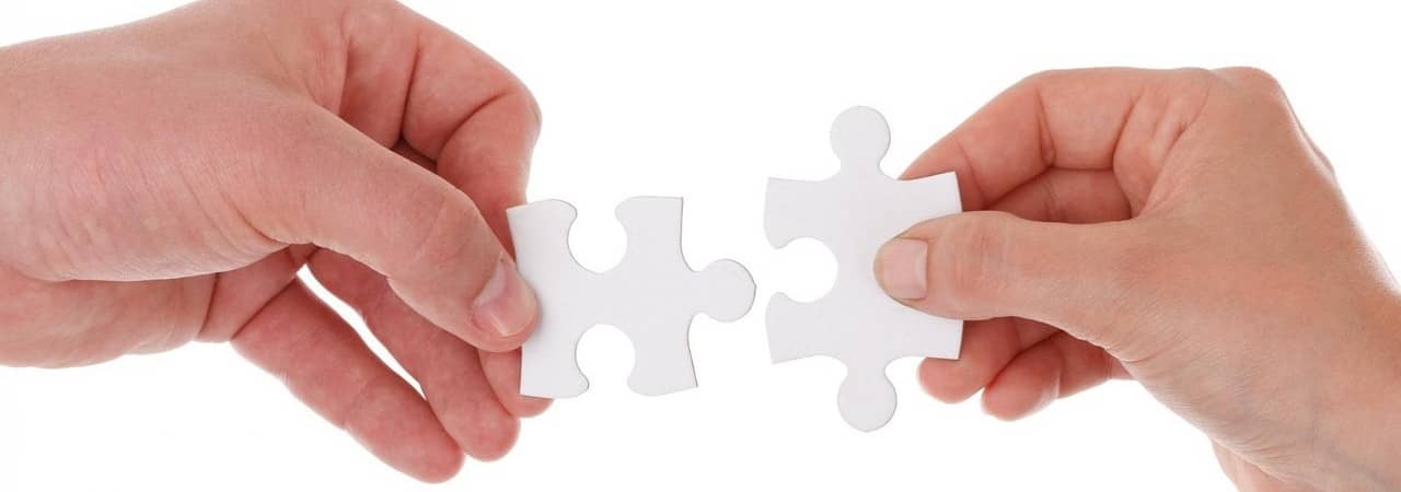 Zwei Hände, welche weisse Puzzleteile nebeneinander halten. Es ist ersichtlich, dass sie zusammenpassen.
