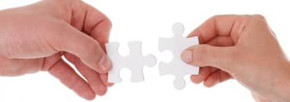 Zwei Hände, welche weisse Puzzleteile nebeneinander halten. Es ist ersichtlich, dass sie zusammenpassen.