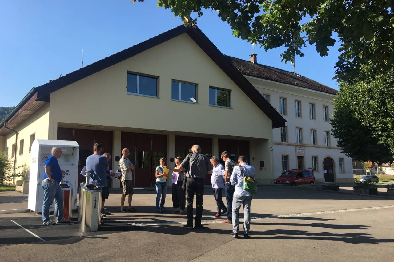 Begleitgruppe und Planende stehen auf dem Platz vor dem Feuerwehrhaus.