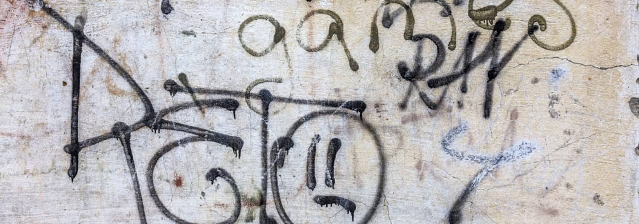 Grafitischriftzüge an einer grauen Wand.